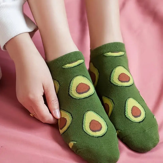 Cute socks with avocado pattern worn by a person on a pink background