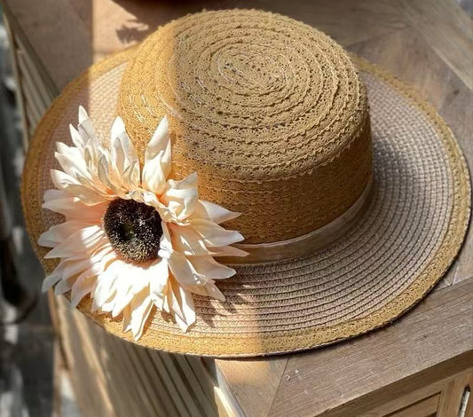Shop our classic tan sun hat, crafted from a breathable cotton and papyrus blend. Features a beautiful creamy-peach sunflower and elegant lace-like weave.