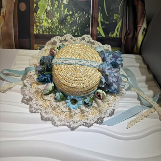 Shop the Celeste, our vintage-inspired straw hat with blue flowers, a wide lace brim, and satin tie ribbons. Perfect for Regency, cottagecore, or "something blue" wedding style.