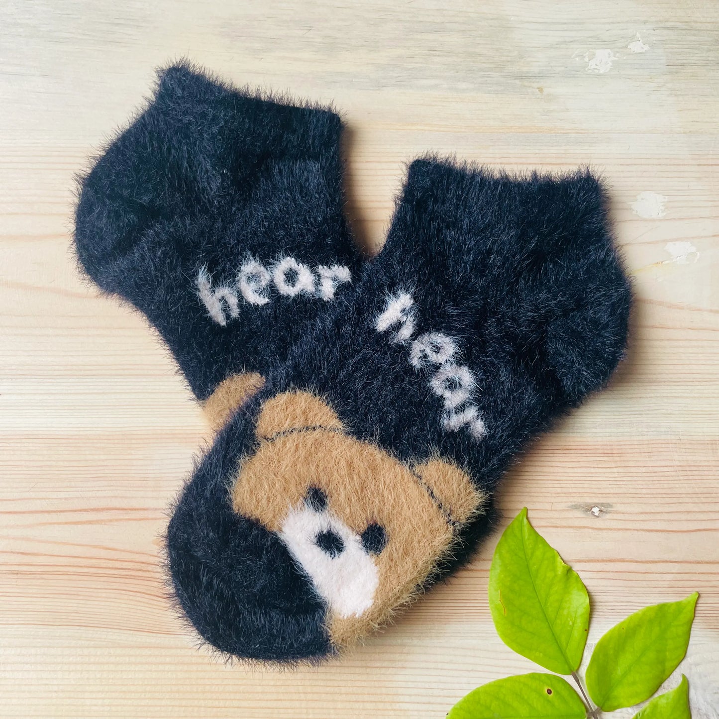 A pair of soft black unisex fuzzy mink socks with a cute bear face design, perfect for winter.