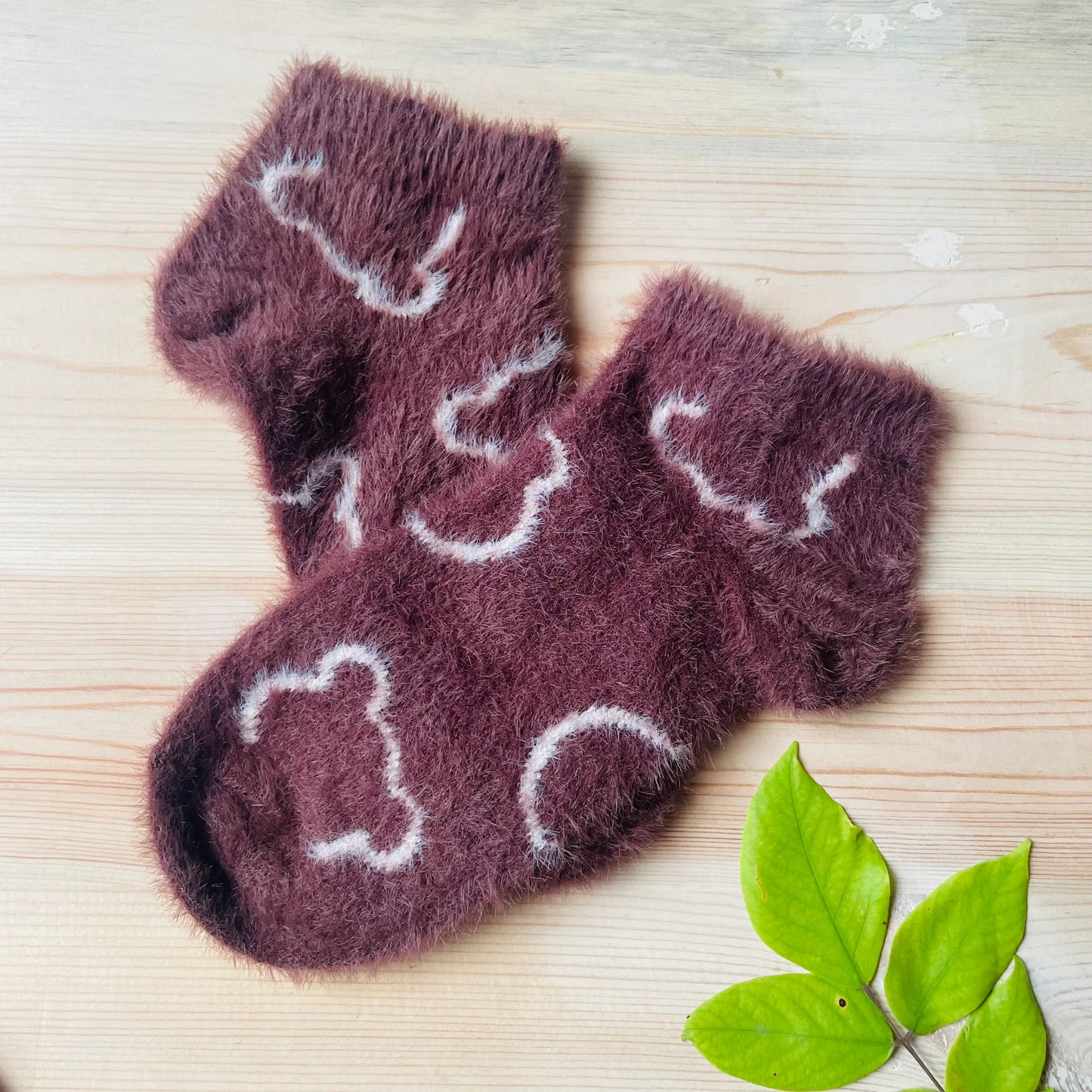 A pair of dark brown fluffy mink unisex house socks with a white bear outline pattern.