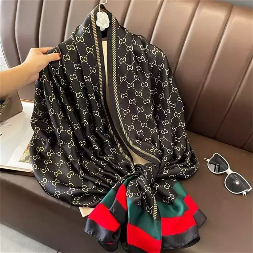 Discover timeless style with this luxurious silk-feel satin scarf. Featuring a classic black and gold monogram and an iconic red and green striped border, this 90 x 180 cm scarf is the epitome of elegance.