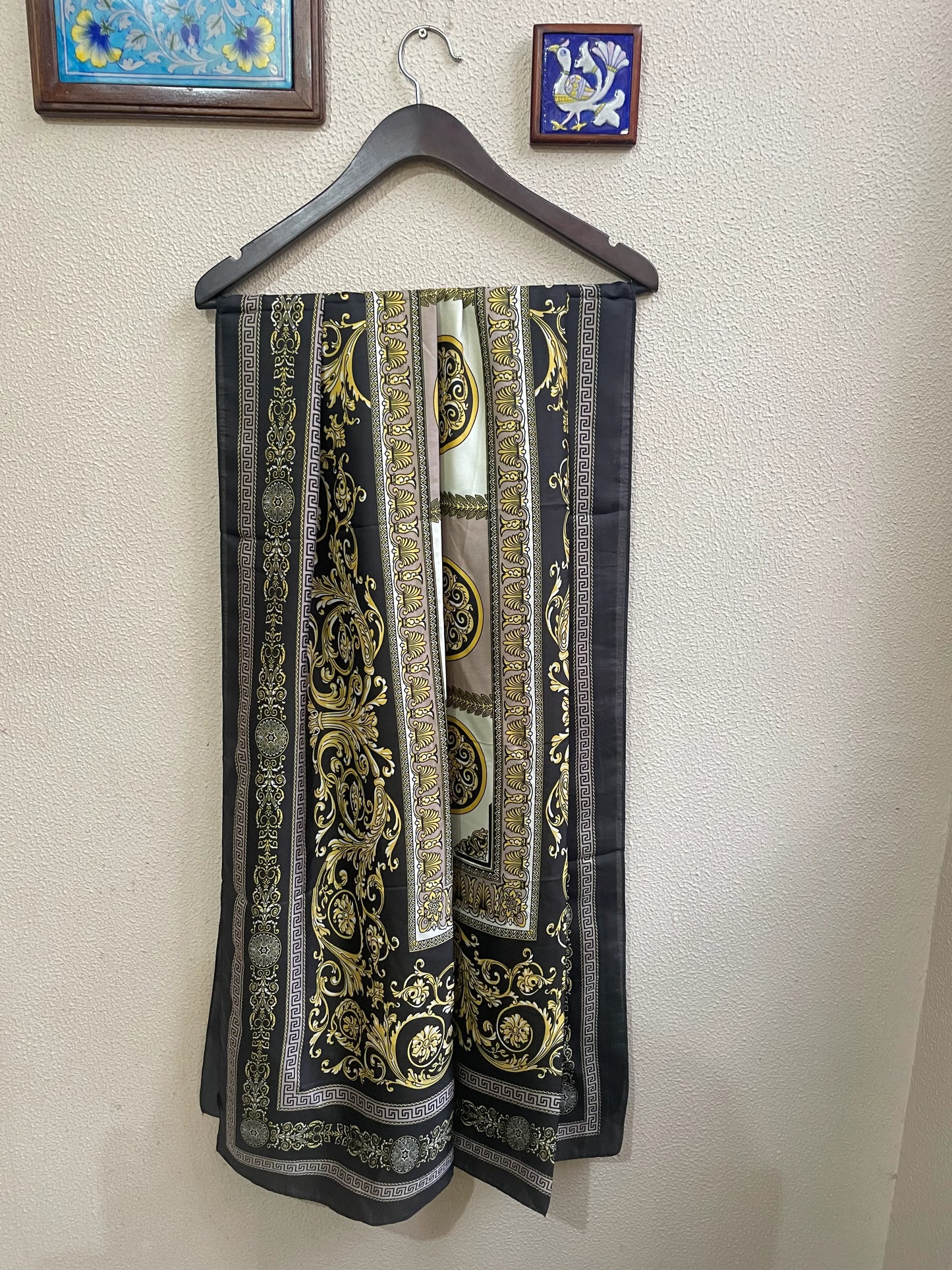 Indulge in luxury with this stunning silk-feel satin scarf. Features an ornate gold and black baroque scrollwork pattern with a Greek key border. Measures 90 x 180 cm. Perfect for adding a touch of regal elegance.