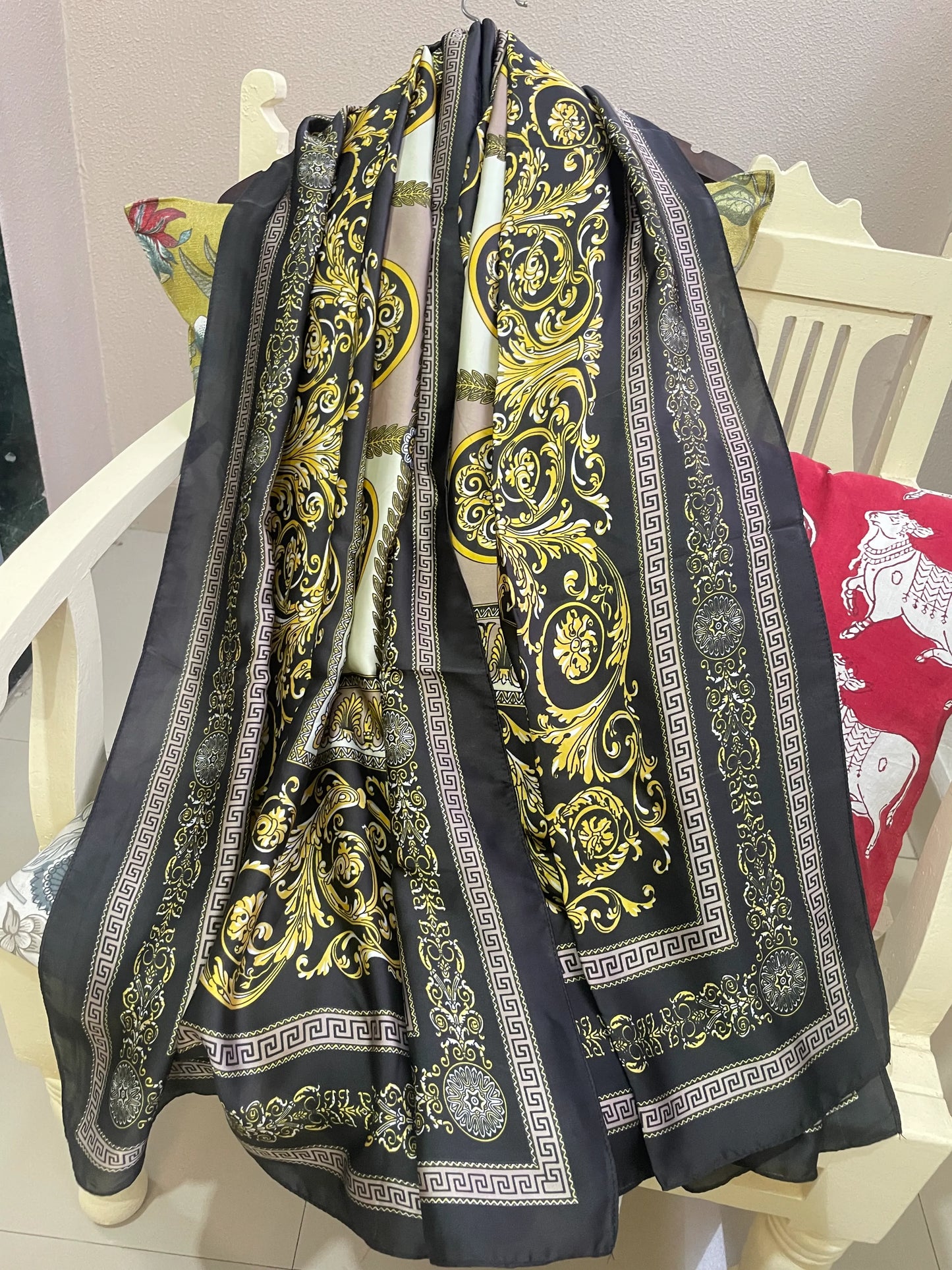 Indulge in luxury with this stunning silk-feel satin scarf. Features an ornate gold and black baroque scrollwork pattern with a Greek key border. Measures 90 x 180 cm. Perfect for adding a touch of regal elegance.