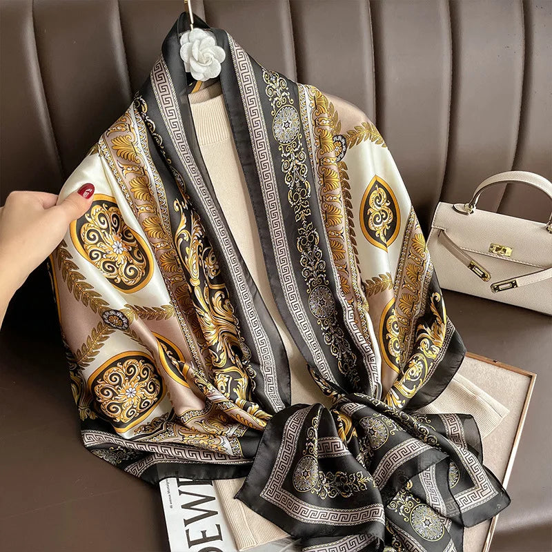 Indulge in luxury with this stunning silk-feel satin scarf. Features an ornate gold and black baroque scrollwork pattern with a Greek key border. Measures 90 x 180 cm. Perfect for adding a touch of regal elegance.