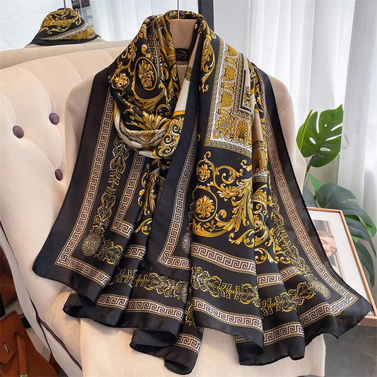 Indulge in luxury with this stunning silk-feel satin scarf. Features an ornate gold and black baroque scrollwork pattern with a Greek key border. Measures 90 x 180 cm. Perfect for adding a touch of regal elegance.
