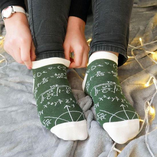 Person wearing green socks with mathematical equations on a soft surface.