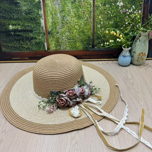 Rustic beige wide-brim sun hat with blush roses, greenery, and trailing lace ribbons