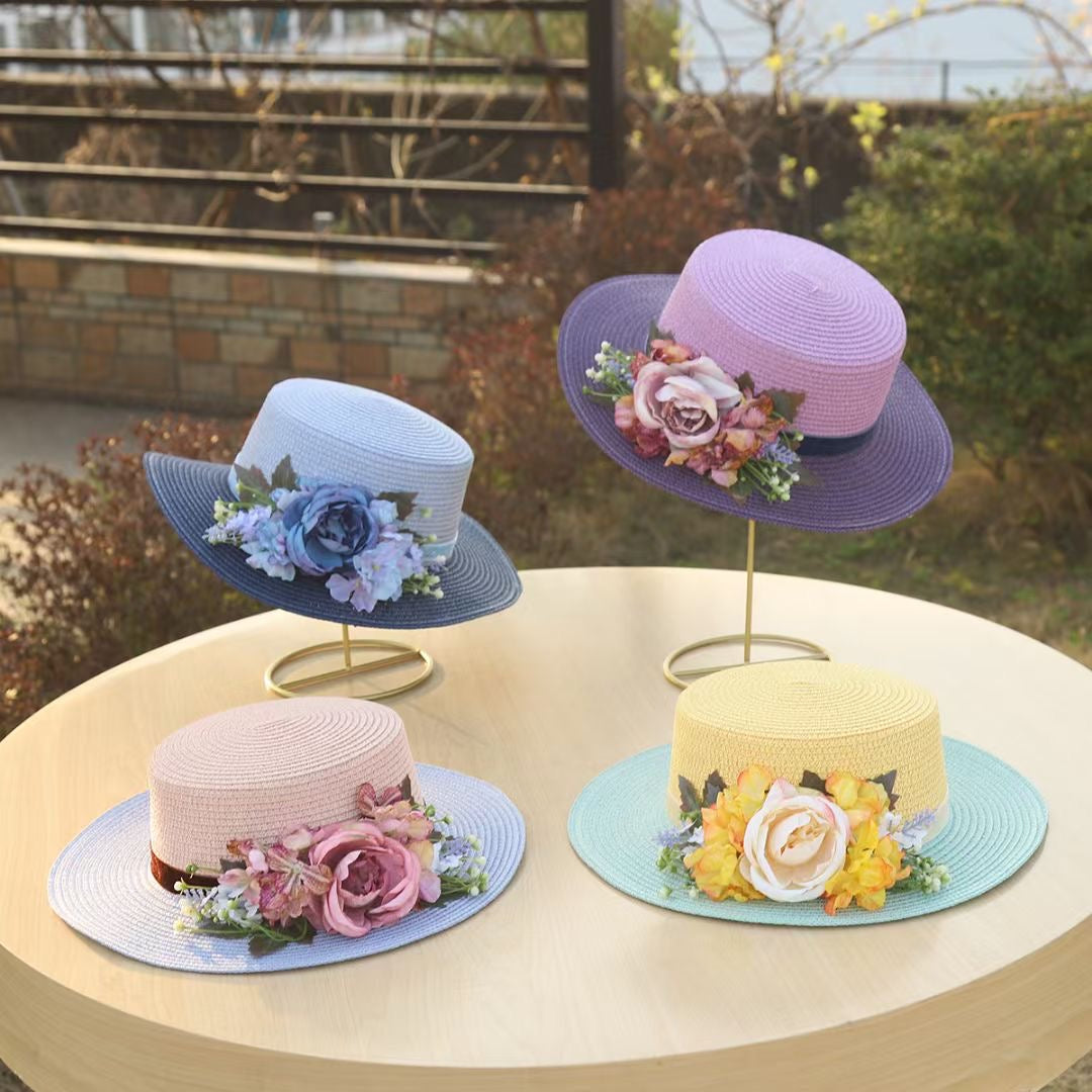 Vintage floral boater hat made of papyrus with l flowers and ribbon, displayed on wicker basket with garden-themed decor.