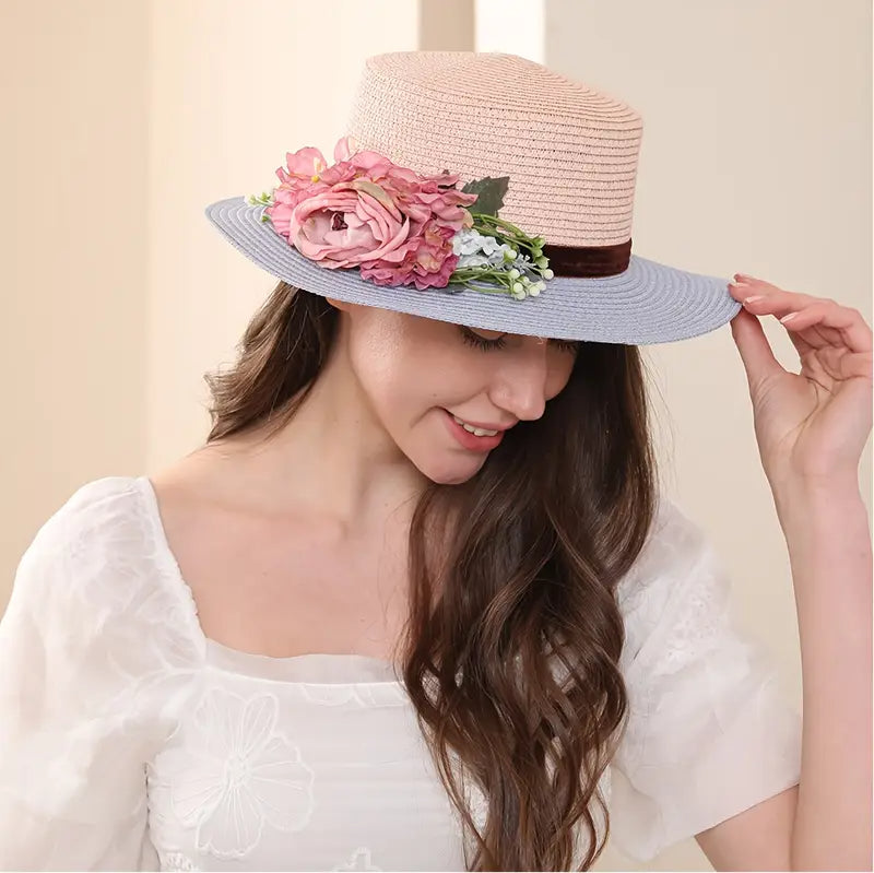 Vintage pink and blue floral boater hat made of papyrus with mauve roses and greenery, displayed on wicker basket with rustic decor.