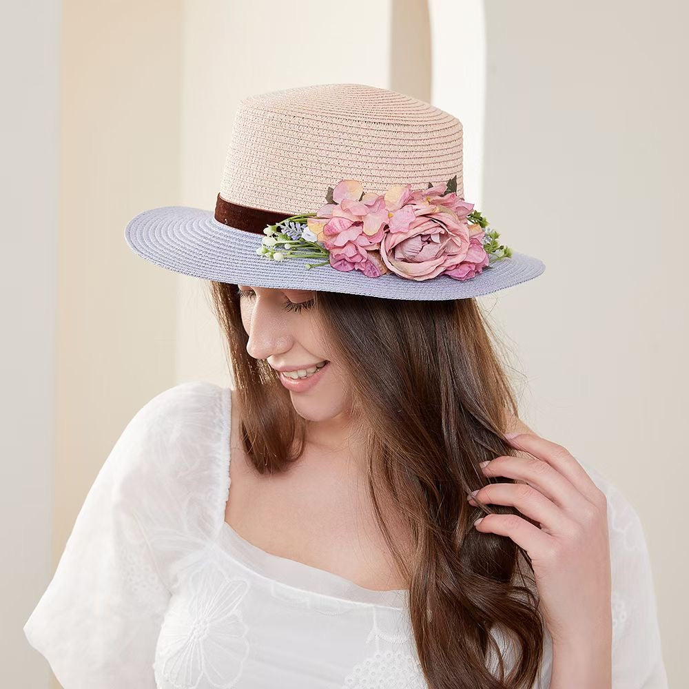 Vintage pink and blue floral boater hat made of papyrus with mauve roses and greenery, displayed on wicker basket with rustic decor.