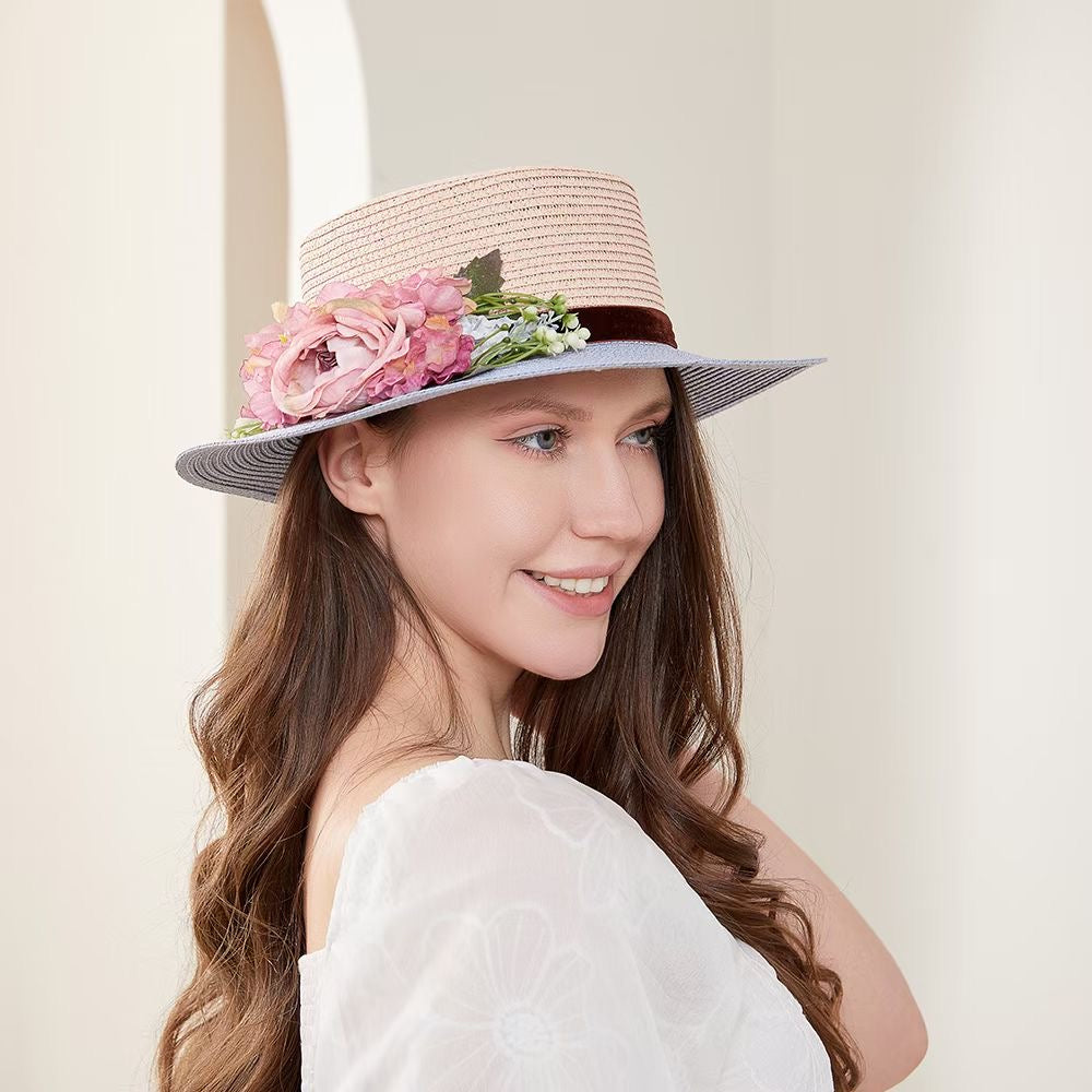 Vintage pink and blue floral boater hat made of papyrus with mauve roses and greenery, displayed on wicker basket with rustic decor.