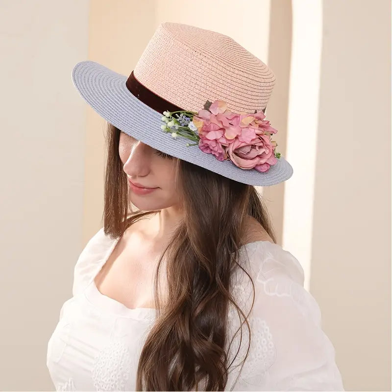 Vintage pink and blue floral boater hat made of papyrus with mauve roses and greenery, displayed on wicker basket with rustic decor.