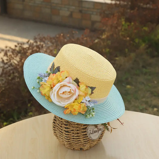 Vintage yellow and blue floral boater hat made of papyrus with yellow blossoms and cream rose, displayed on wicker basket with rustic decor.