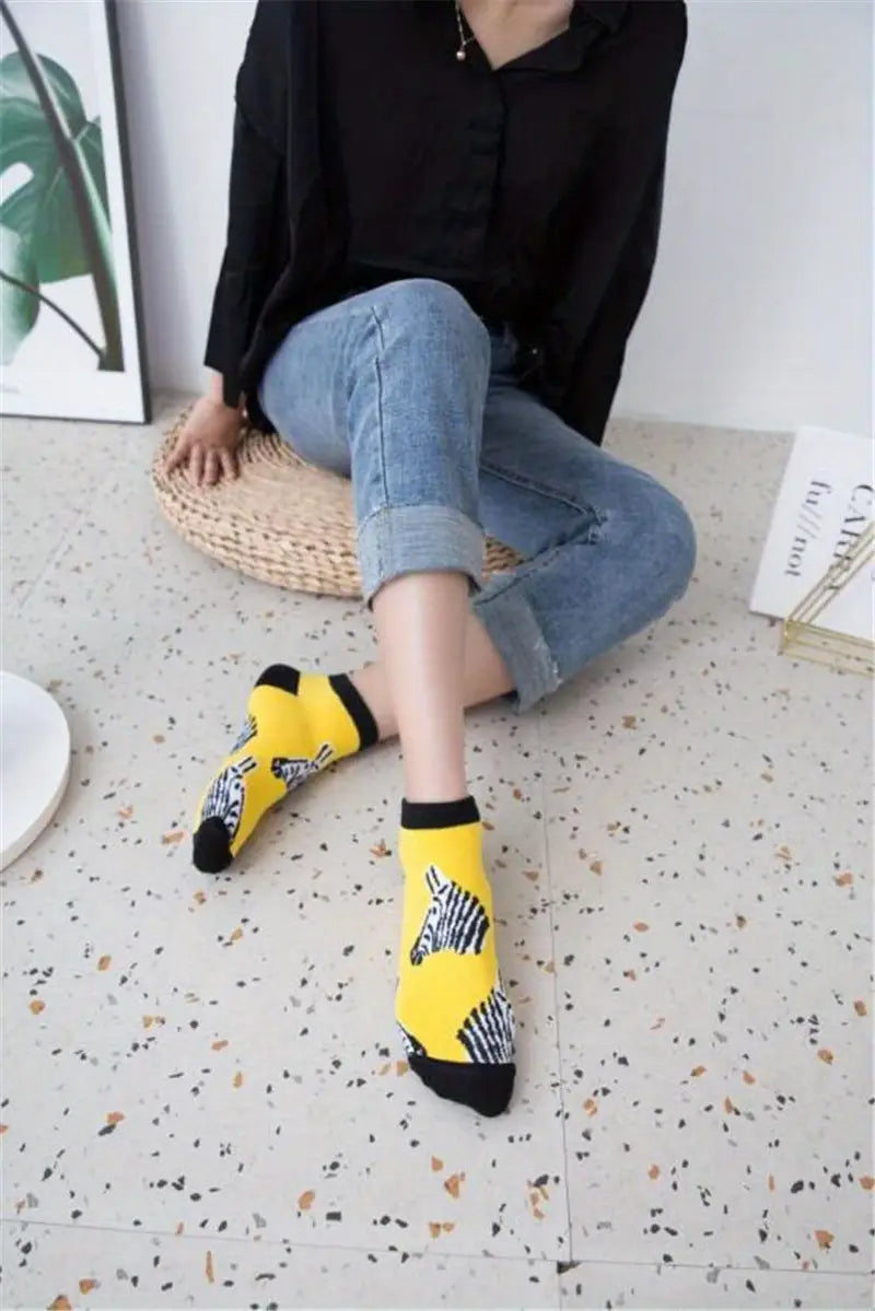 A person wearing yellow socks with zebra patterns is sitting on a textured floor.