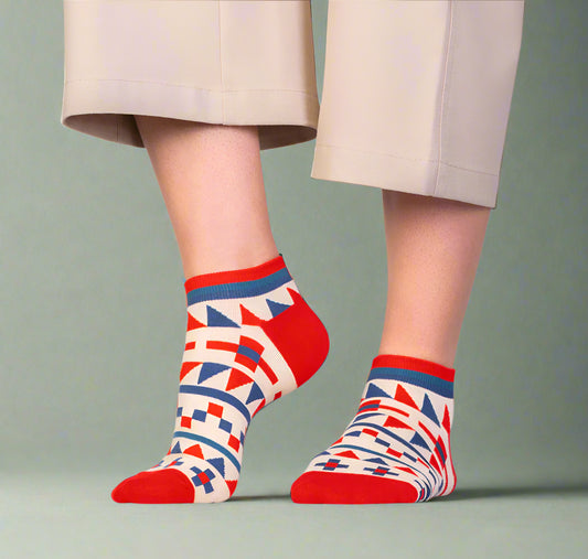 Person wearing patterned socks with a geometric design on a plain background