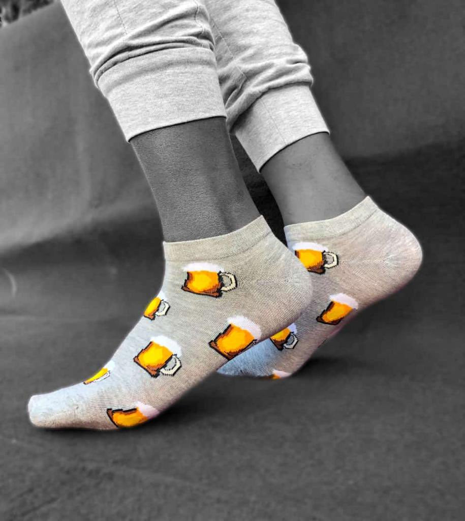 Gray socks with beer mug design worn by a person on a dark background