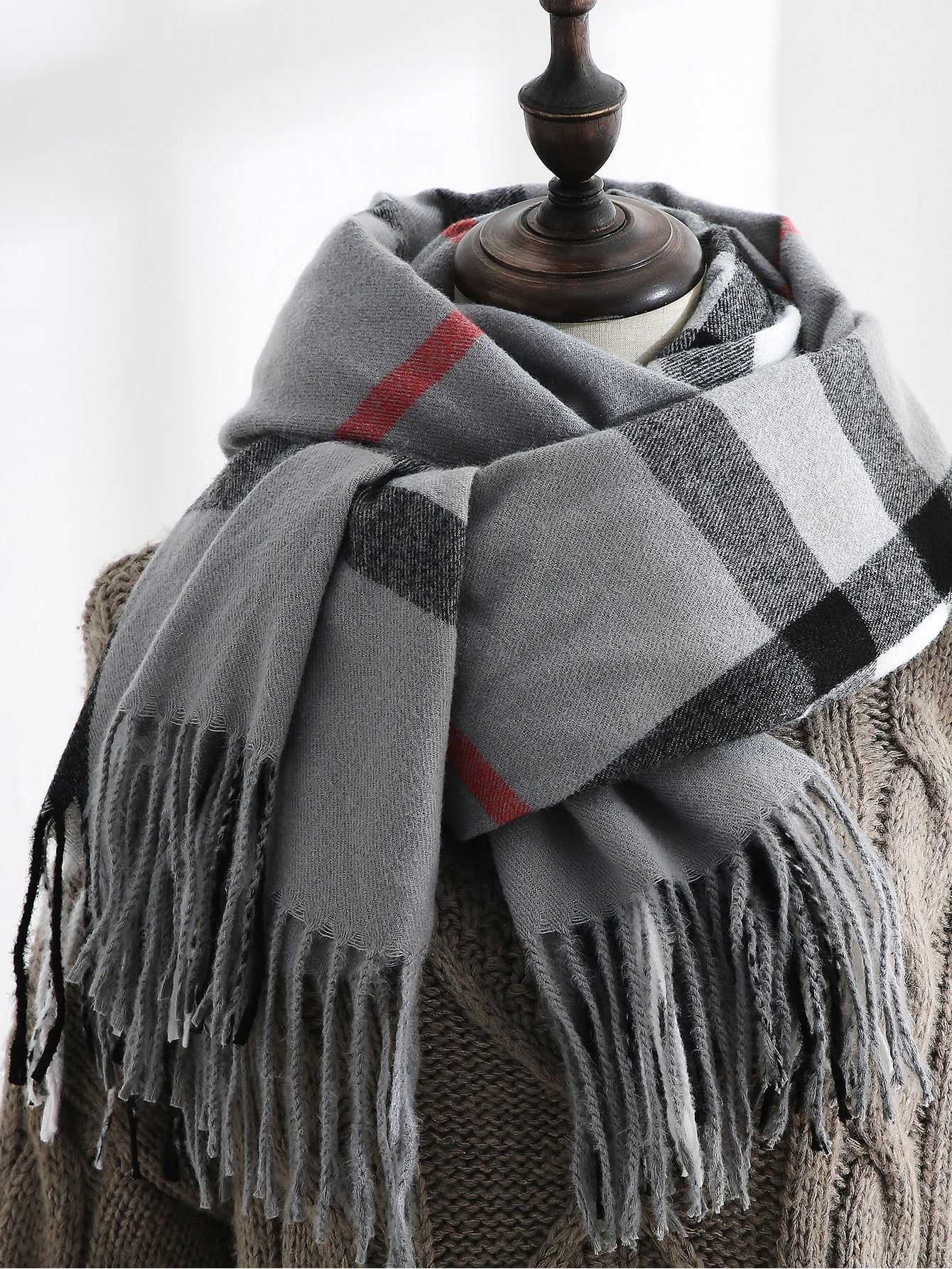 Grey tartan check scarf with red accent lines draped on a mannequin
