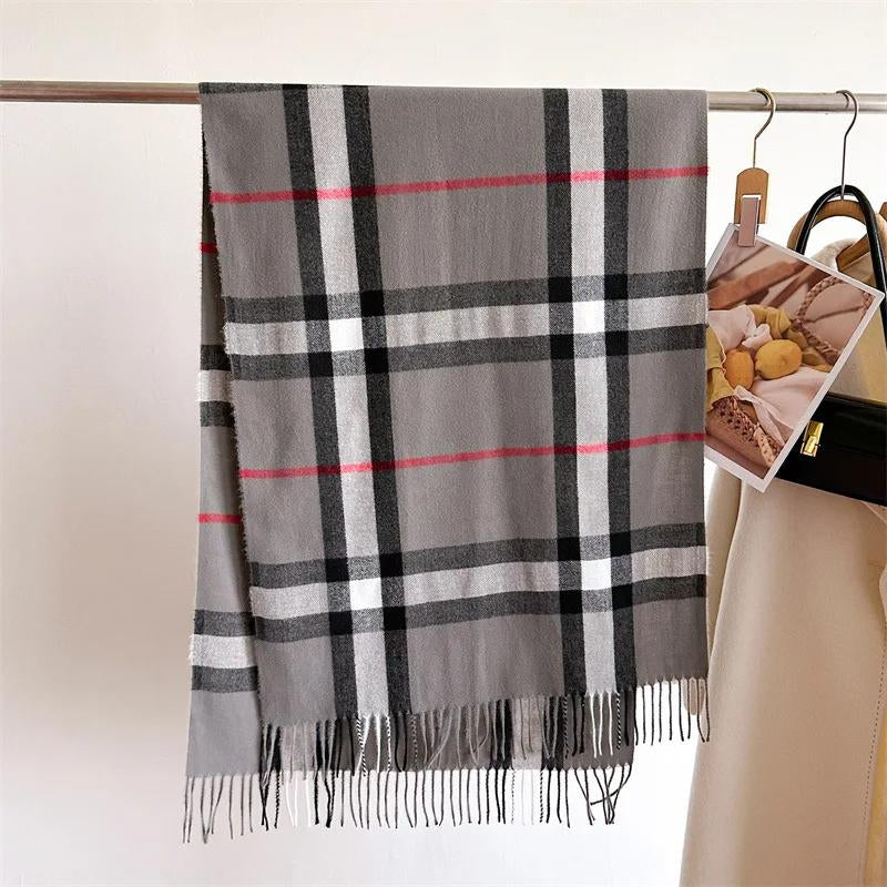 Plaid scarf with gray, black, and red colors hanging on a rack.