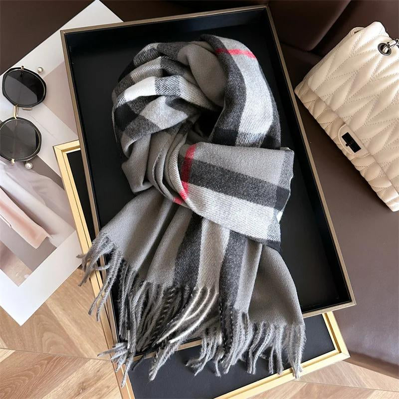 Gray checkered scarf in a black box with sunglasses and a beige pouch on a wooden surface.