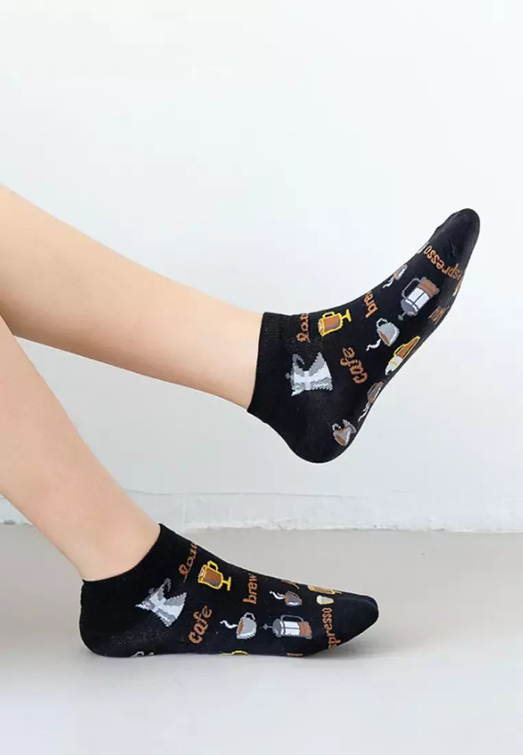 Black socks with coffee-themed design worn by a person on a white background
