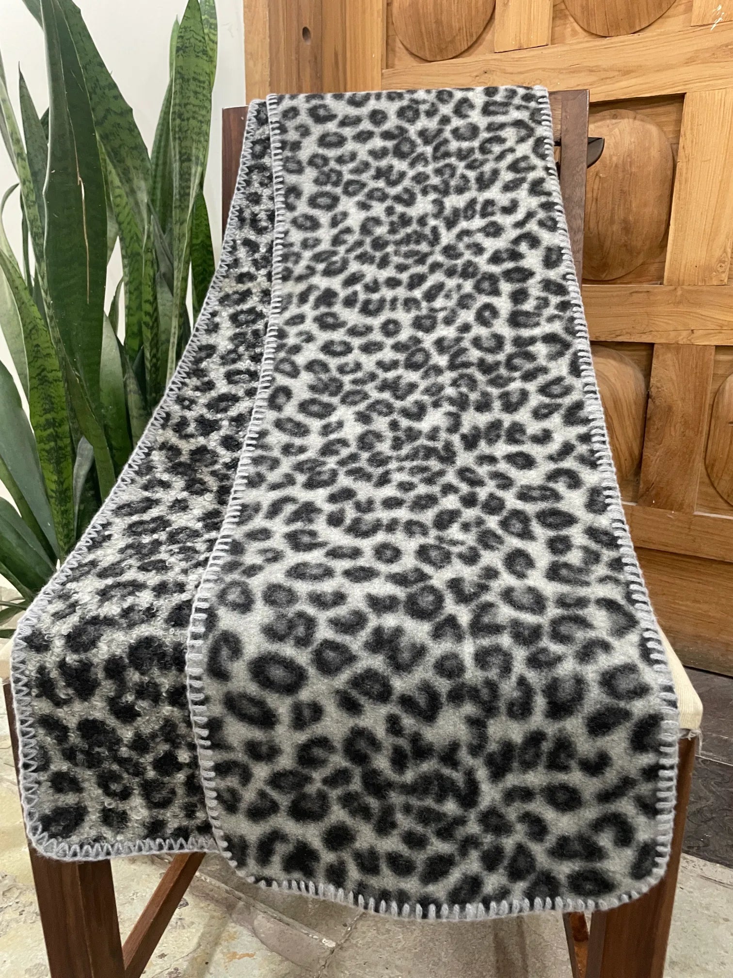 Leopard print scarf on a wooden chair with a plant in the background
