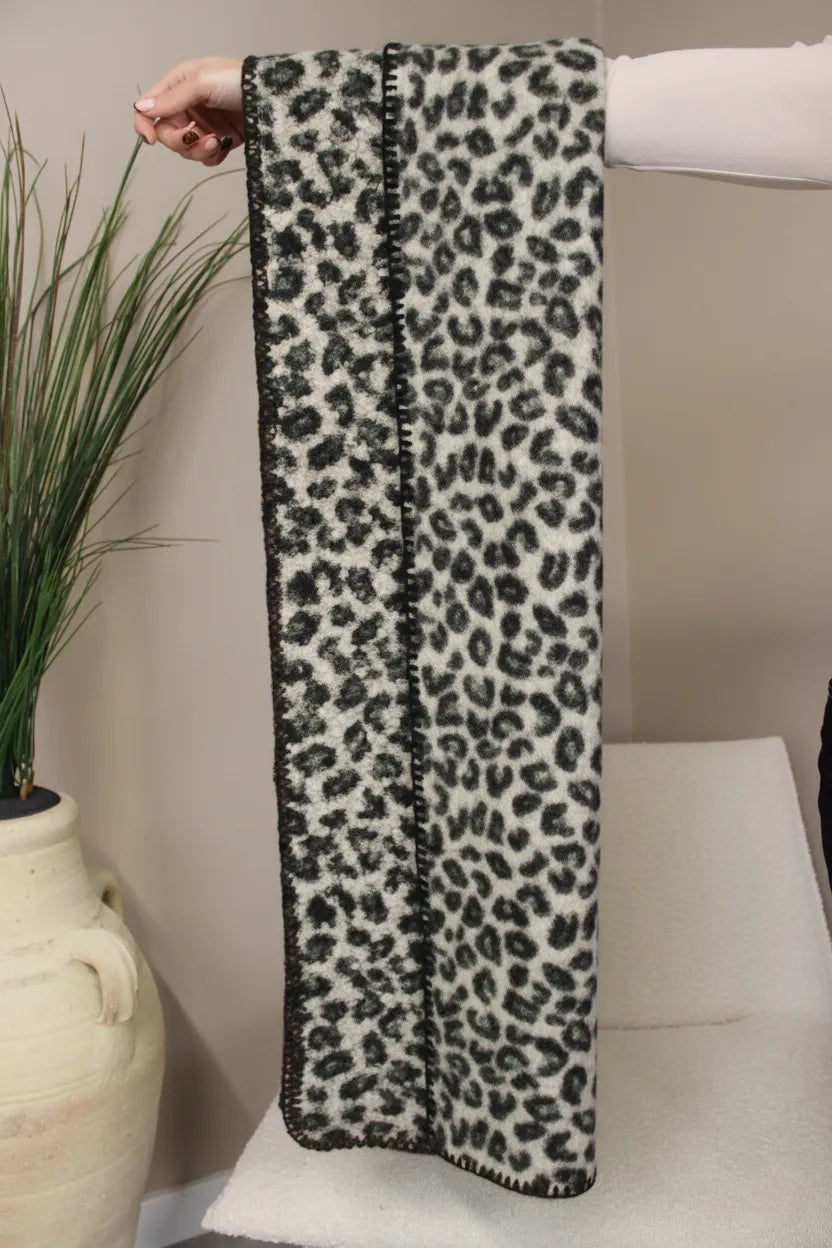 Leopard print beige scarf held by a person against a neutral background