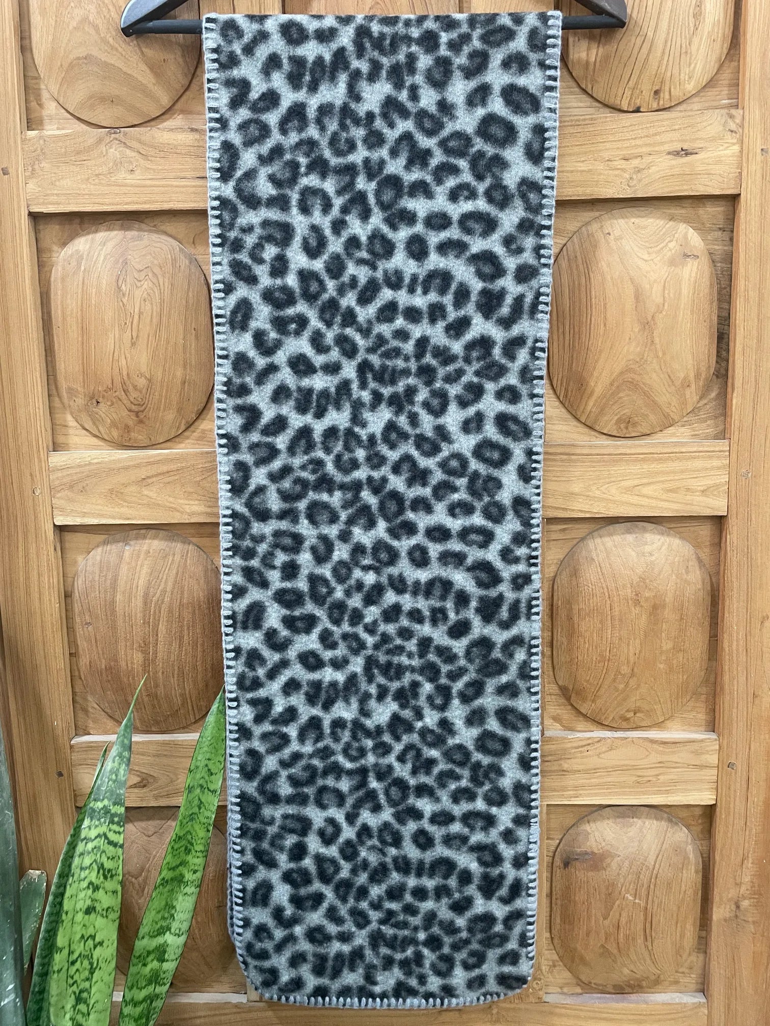 Leopard print scarf on a wooden floor with a plant in the corner
