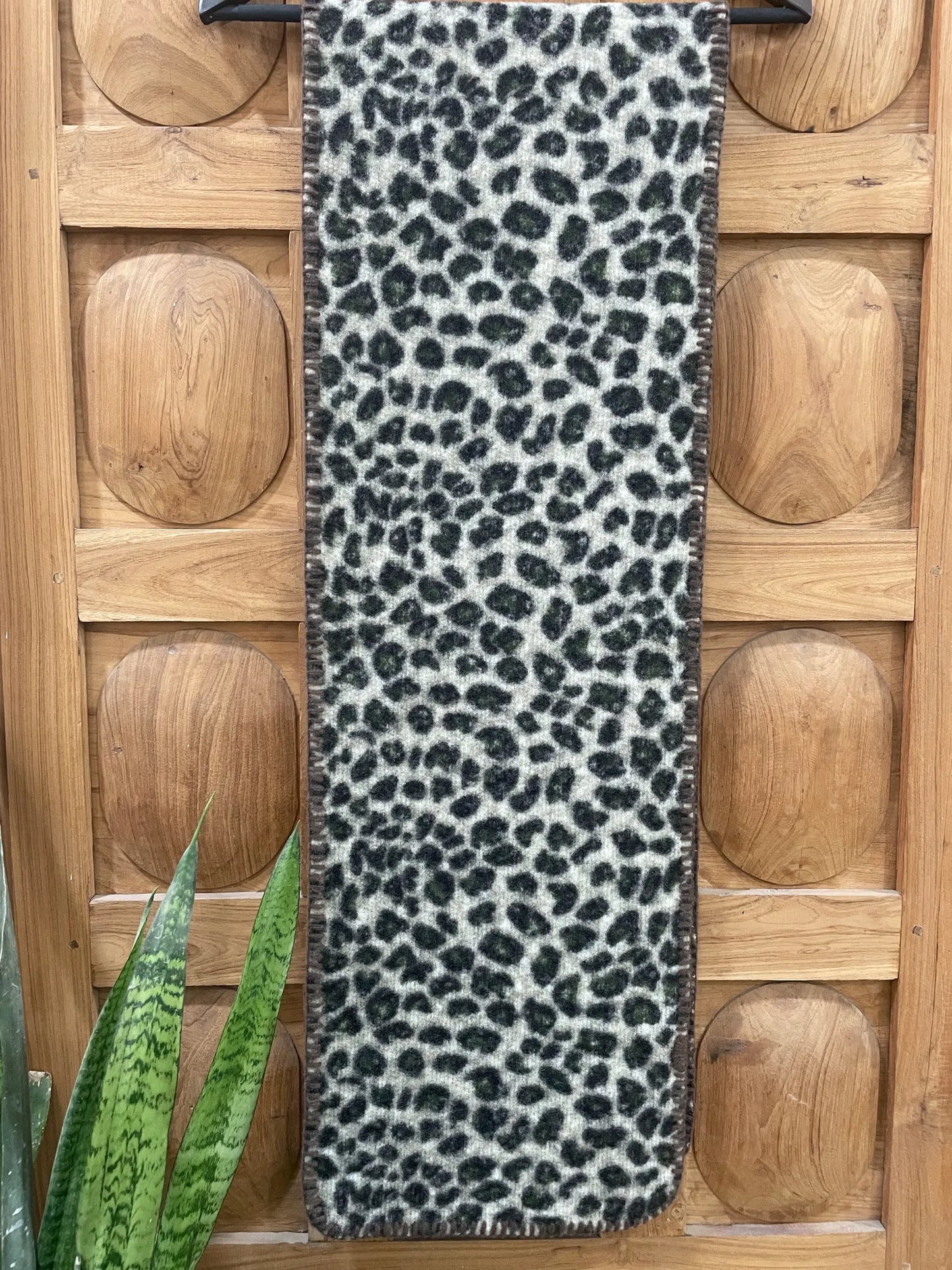 Leopard print scarf on a wooden floor with a plant in the corner