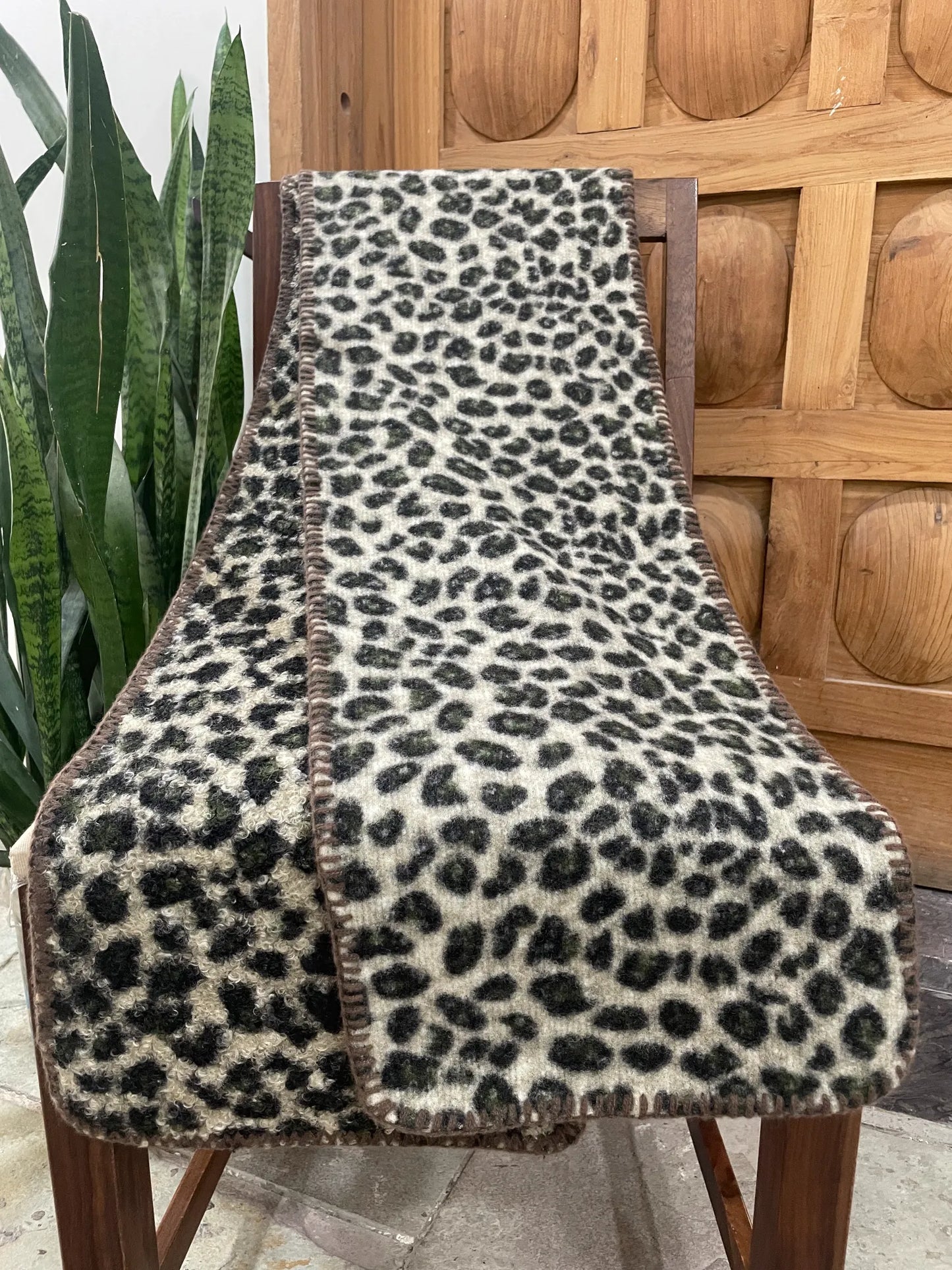 Leopard print scarf on a wooden chair with a plant in the background