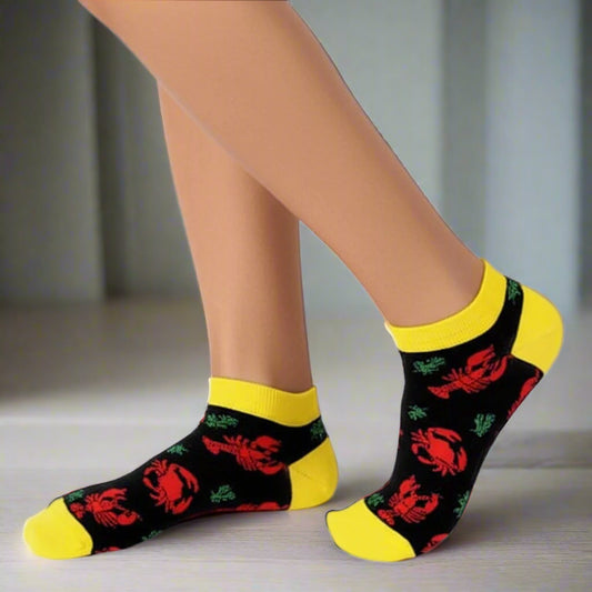 Black socks with red crab patterns and yellow toes worn by a person on a white background