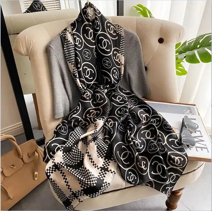 Discover ultimate versatility with this luxurious silk-feel satin scarf. Featuring a unique dual pattern of a chic beige & black check and a classic monogram, this 90 x 180 cm scarf offers multiple styling options.