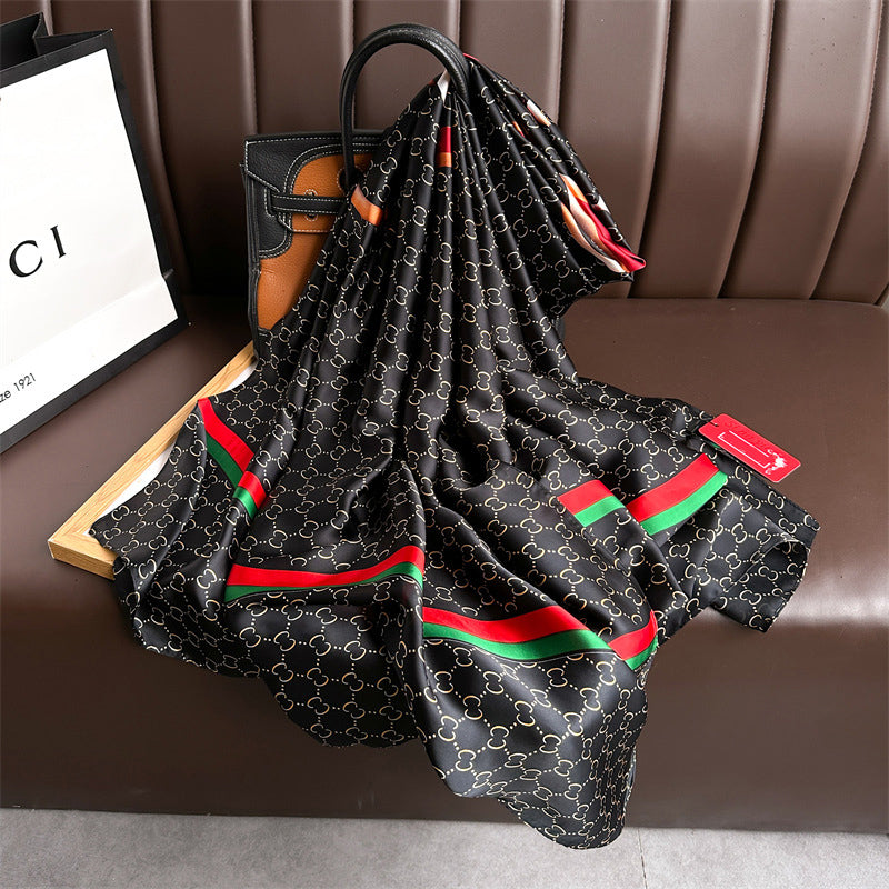 Discover sophistication with this luxurious silk-feel satin scarf. Featuring a black and gold monogram, a bold abstract graphic, and a signature red and green stripe, this 90 x 180 cm scarf is a true statement piece.