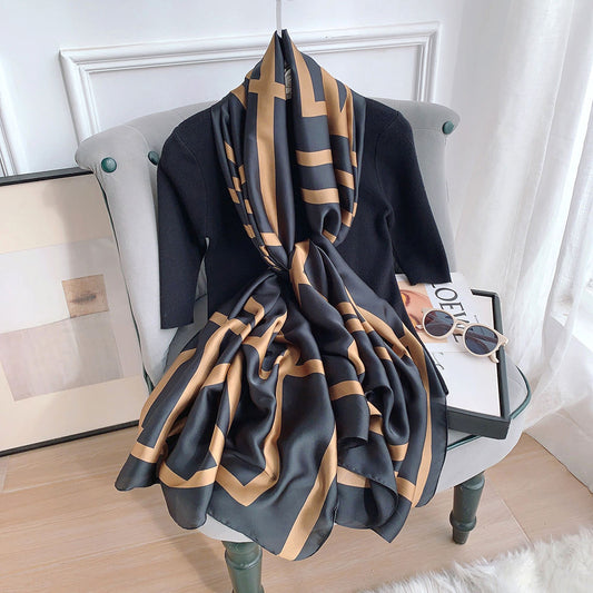 Luxury black and gold bold graphic silk-feel satin scarf tied elegantly over a black top