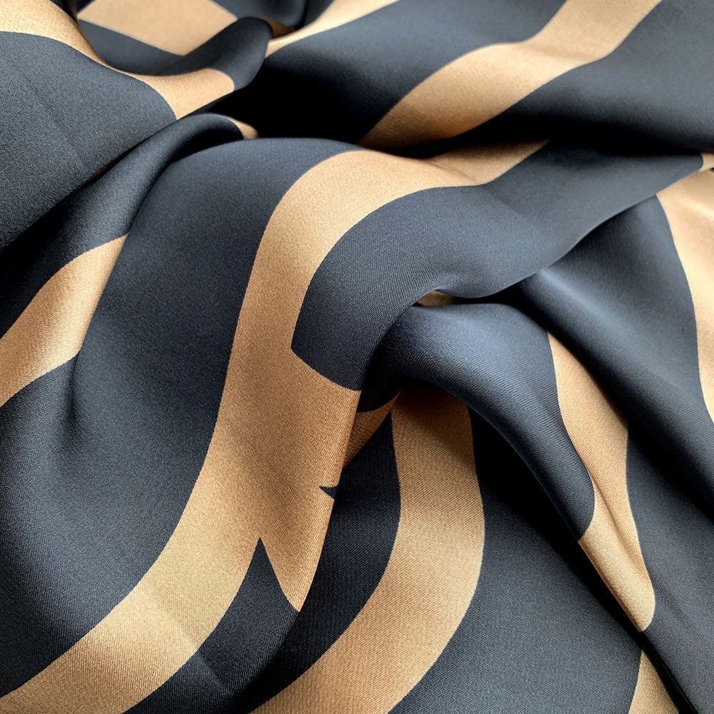 Close-up of the smooth satin texture and bold gold graphic lines on a black background