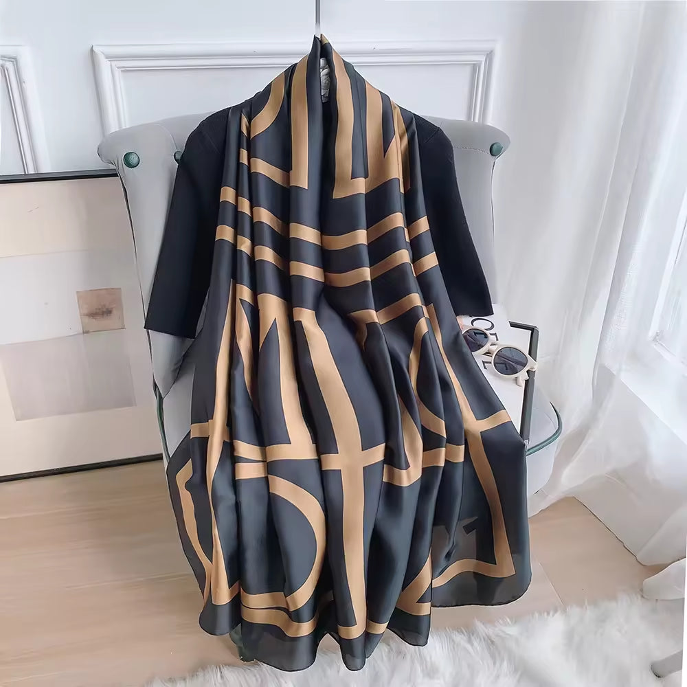 Luxury black and gold bold graphic silk-feel satin scarf tied elegantly over a black top