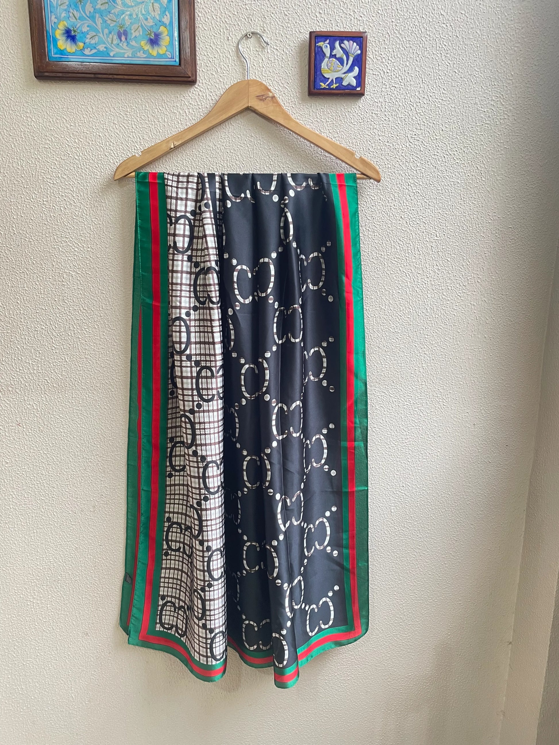 Discover this luxurious silk-feel satin scarf with a unique split design of black and plaid monogram, framed by an iconic red and green border. Measures 90 x 180 cm. The perfect statement accessory.