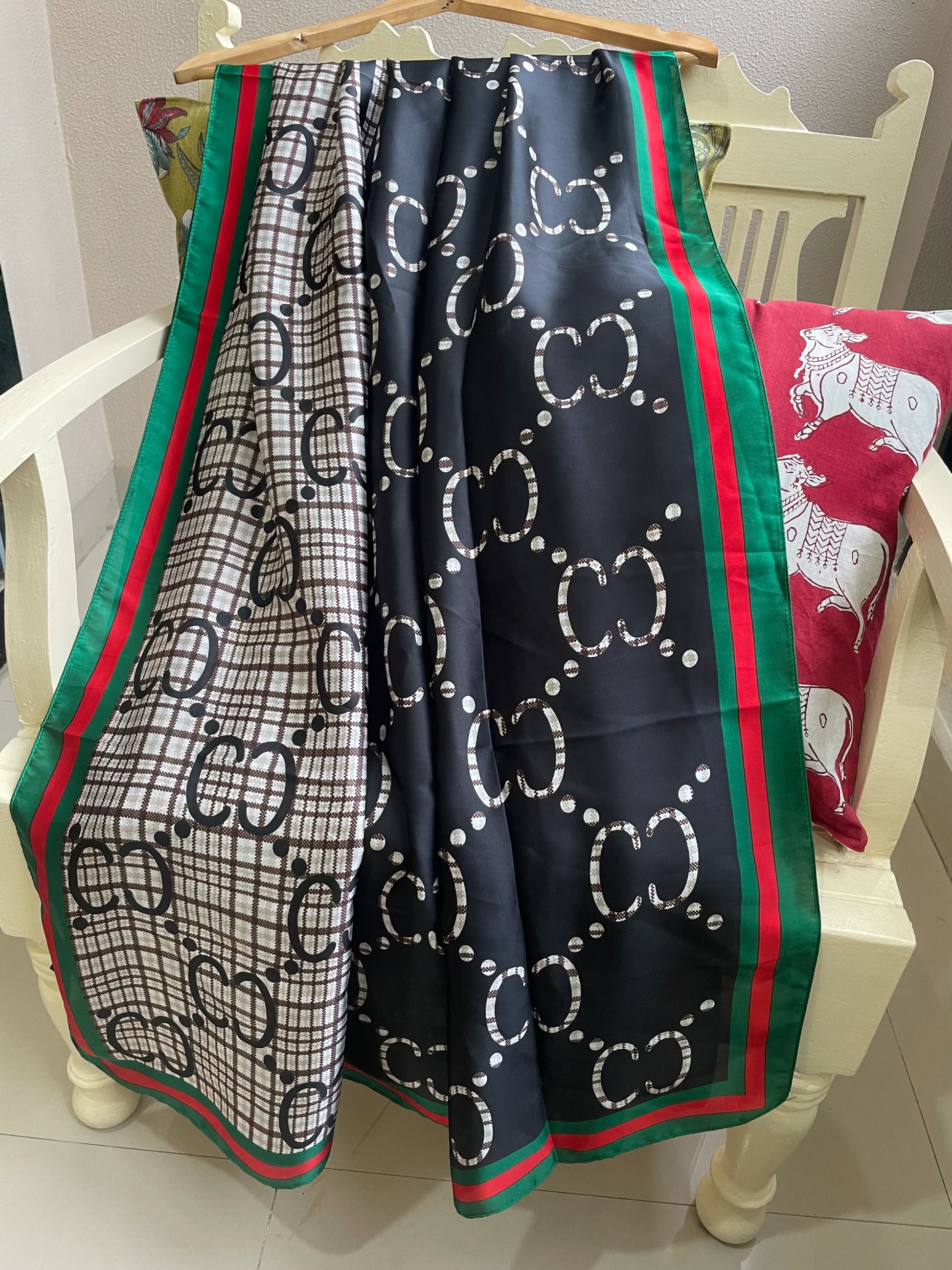 Discover this luxurious silk-feel satin scarf with a unique split design of black and plaid monogram, framed by an iconic red and green border. Measures 90 x 180 cm. The perfect statement accessory.