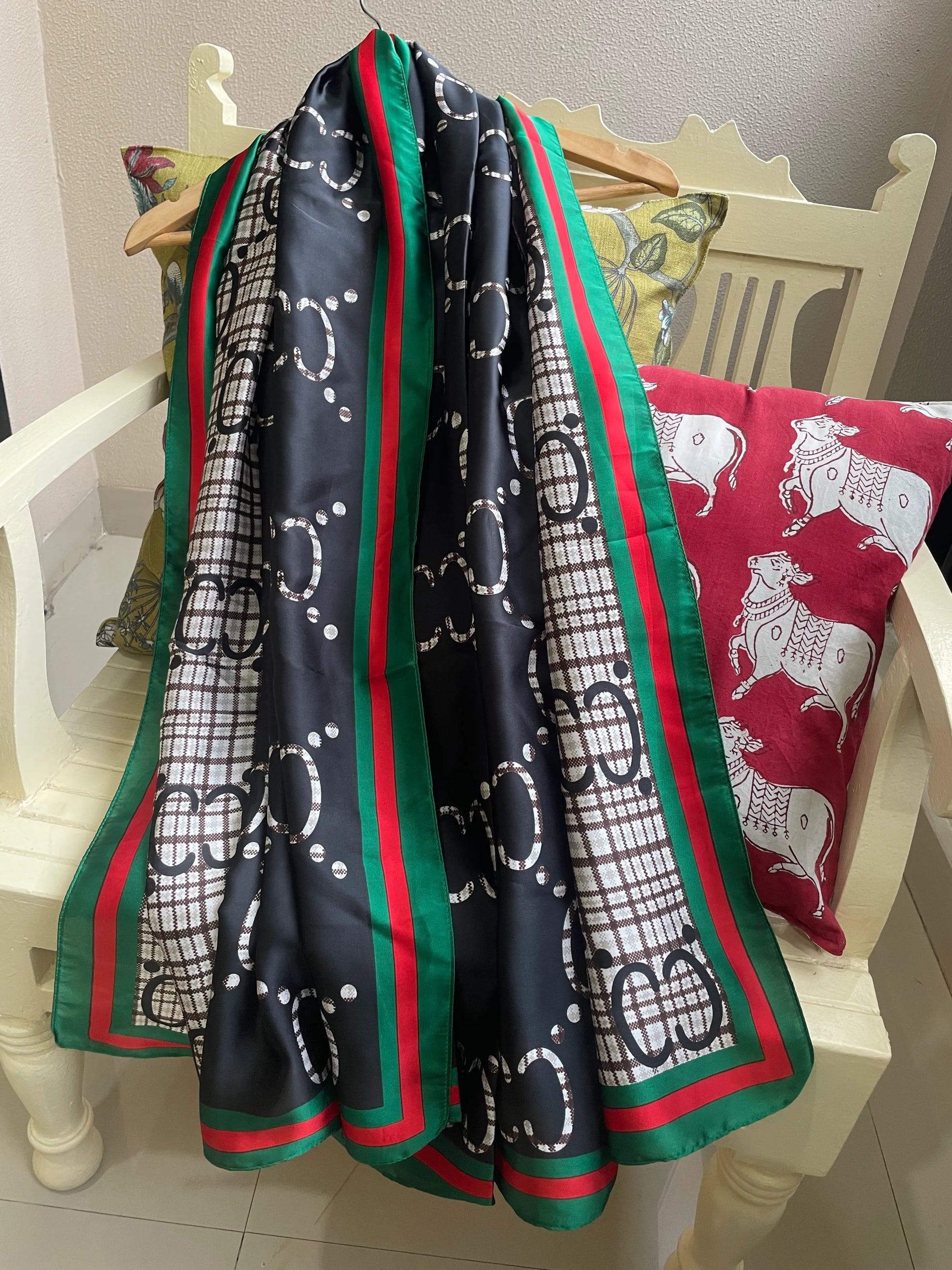 Discover this luxurious silk-feel satin scarf with a unique split design of black and plaid monogram, framed by an iconic red and green border. Measures 90 x 180 cm. The perfect statement accessory.