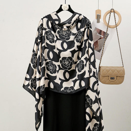 Discover timeless chic with this luxurious silk-feel satin scarf. Features a striking black and white design blending camellia flowers with a bold monogram pattern. Measures 90 x 180 cm. The perfect sophisticated accessory.