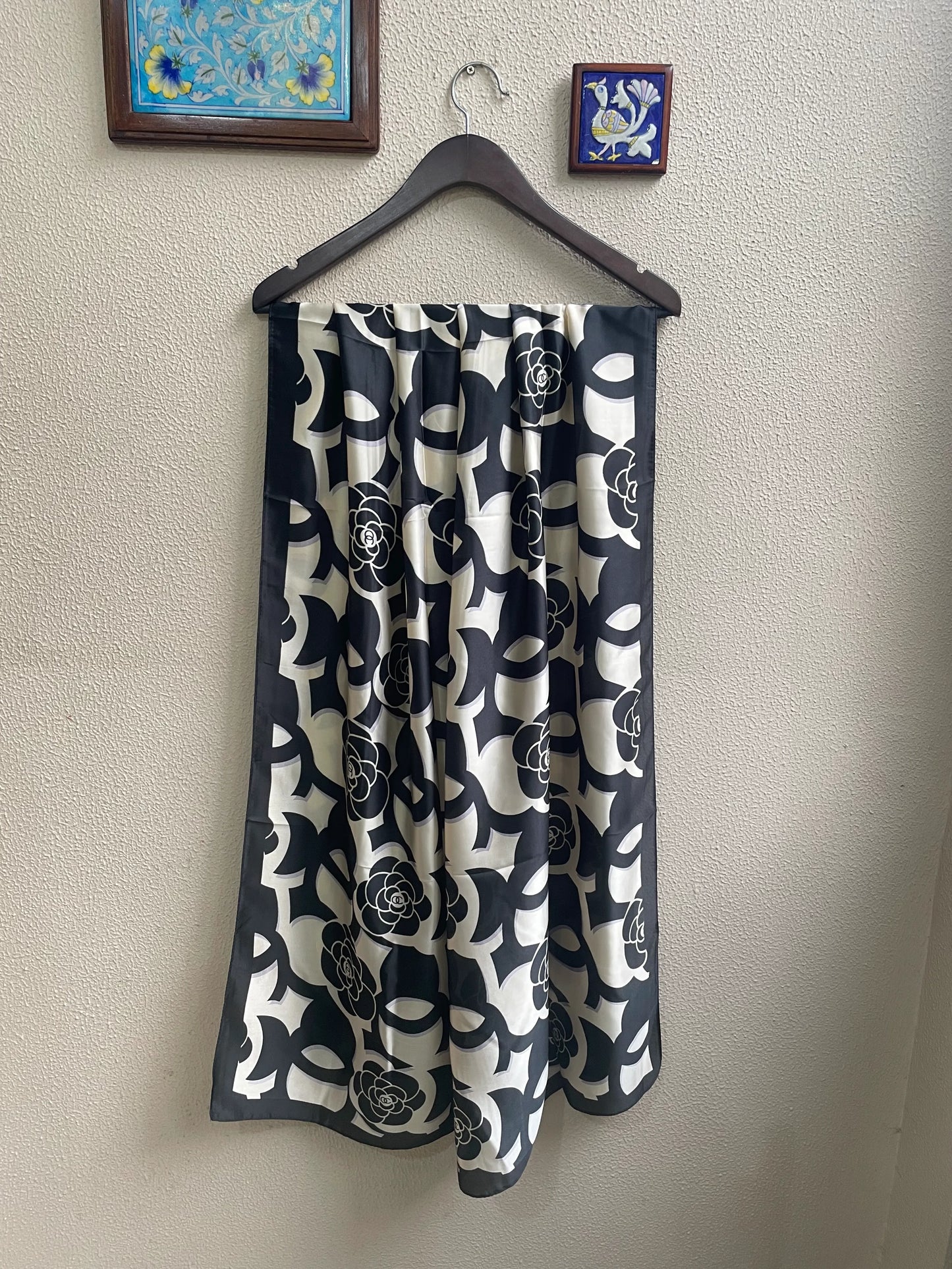 Discover timeless chic with this luxurious silk-feel satin scarf. Features a striking black and white design blending camellia flowers with a bold monogram pattern. Measures 90 x 180 cm. The perfect sophisticated accessory.