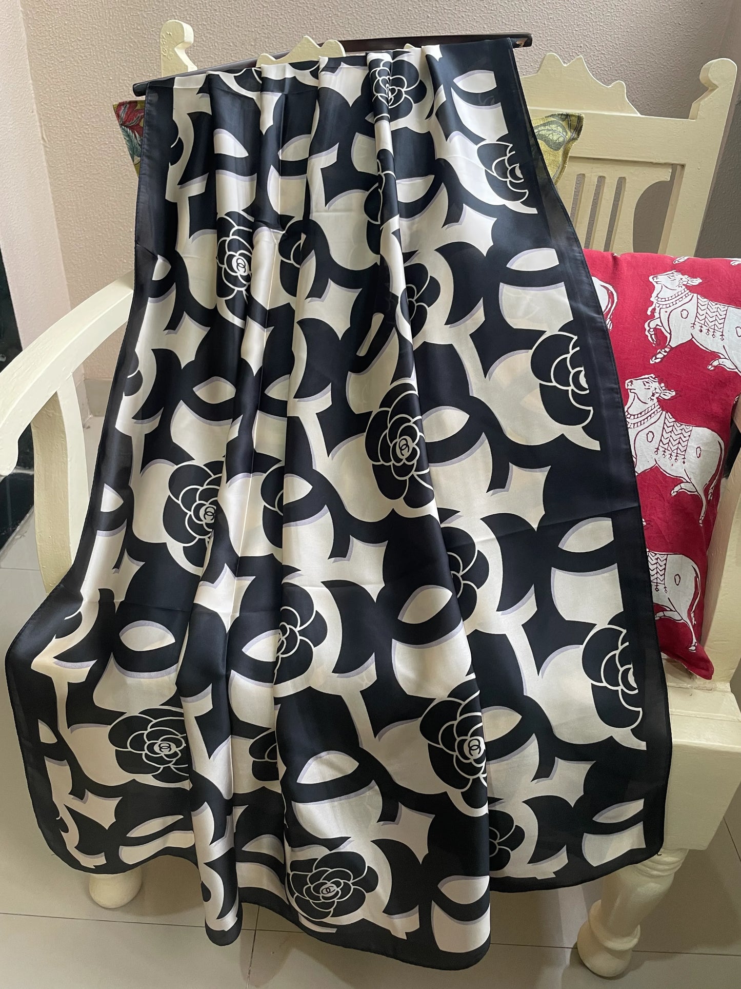 Discover timeless chic with this luxurious silk-feel satin scarf. Features a striking black and white design blending camellia flowers with a bold monogram pattern. Measures 90 x 180 cm. The perfect sophisticated accessory.