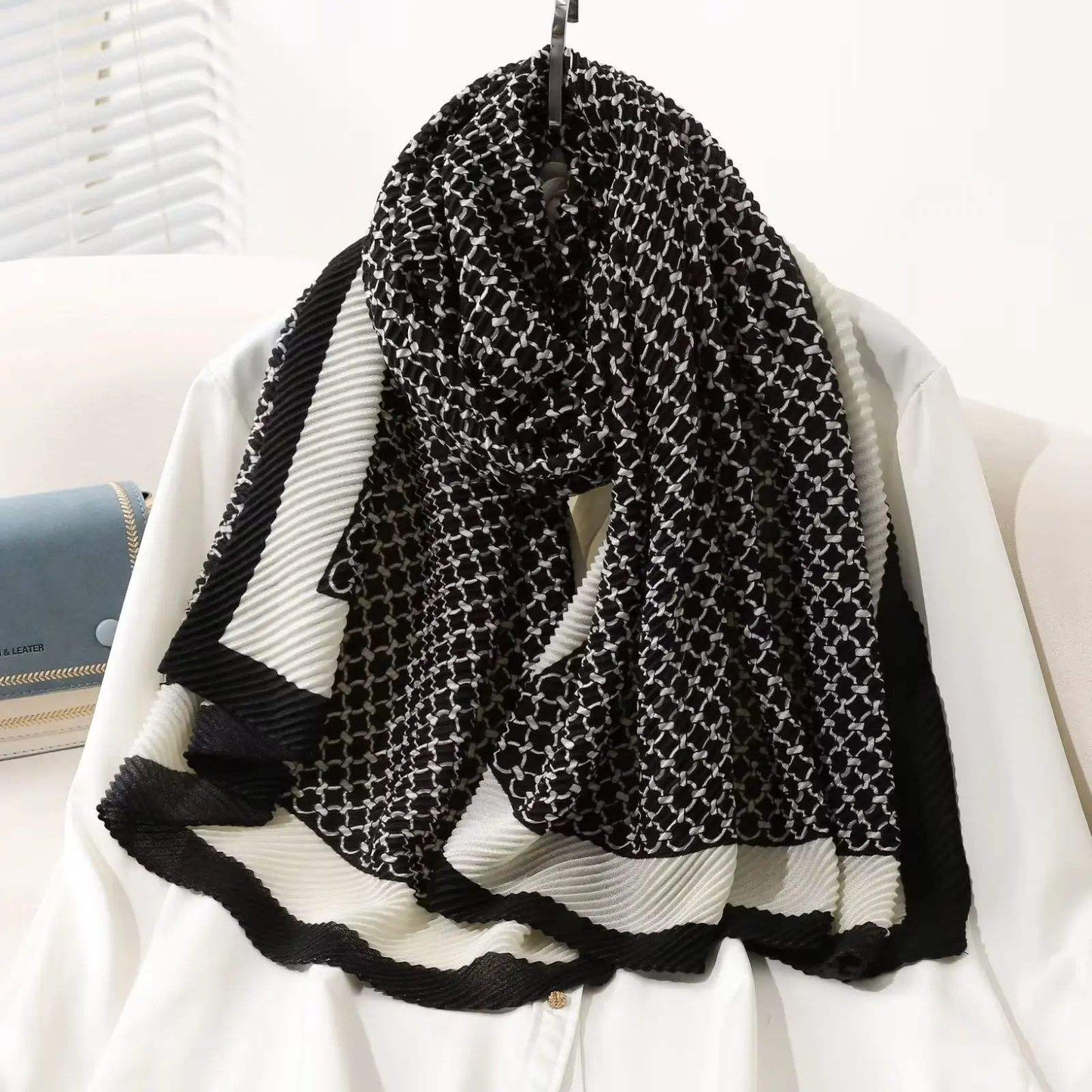 Luxury black and white geometric pattern pleated scarf draped on a mannequin
