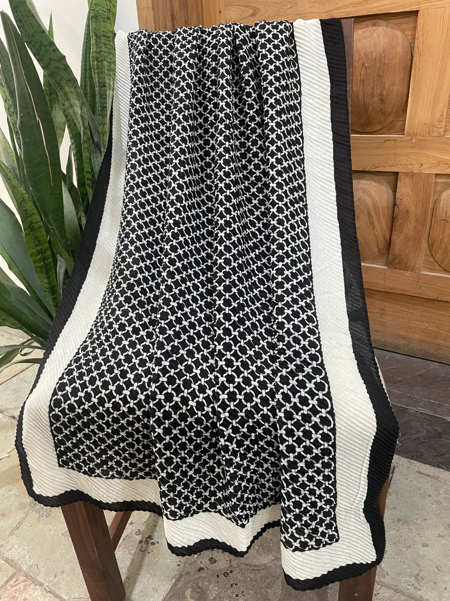 Full length view of black and white lattice design pleated scarf hanging on a chair