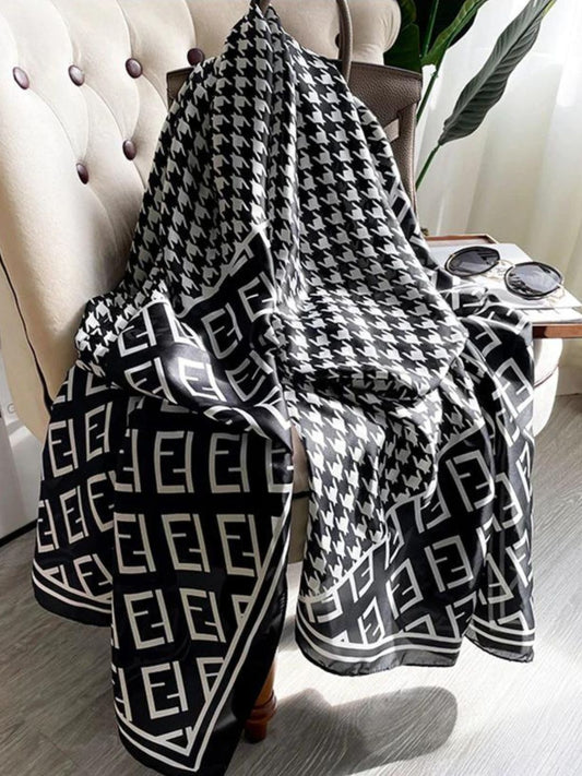 Elevate your wardrobe with this luxurious silk-feel satin scarf. Featuring a timeless black and white houndstooth pattern complemented by a modern monogram border, this 90 x 180 cm scarf is the definition of chic.
