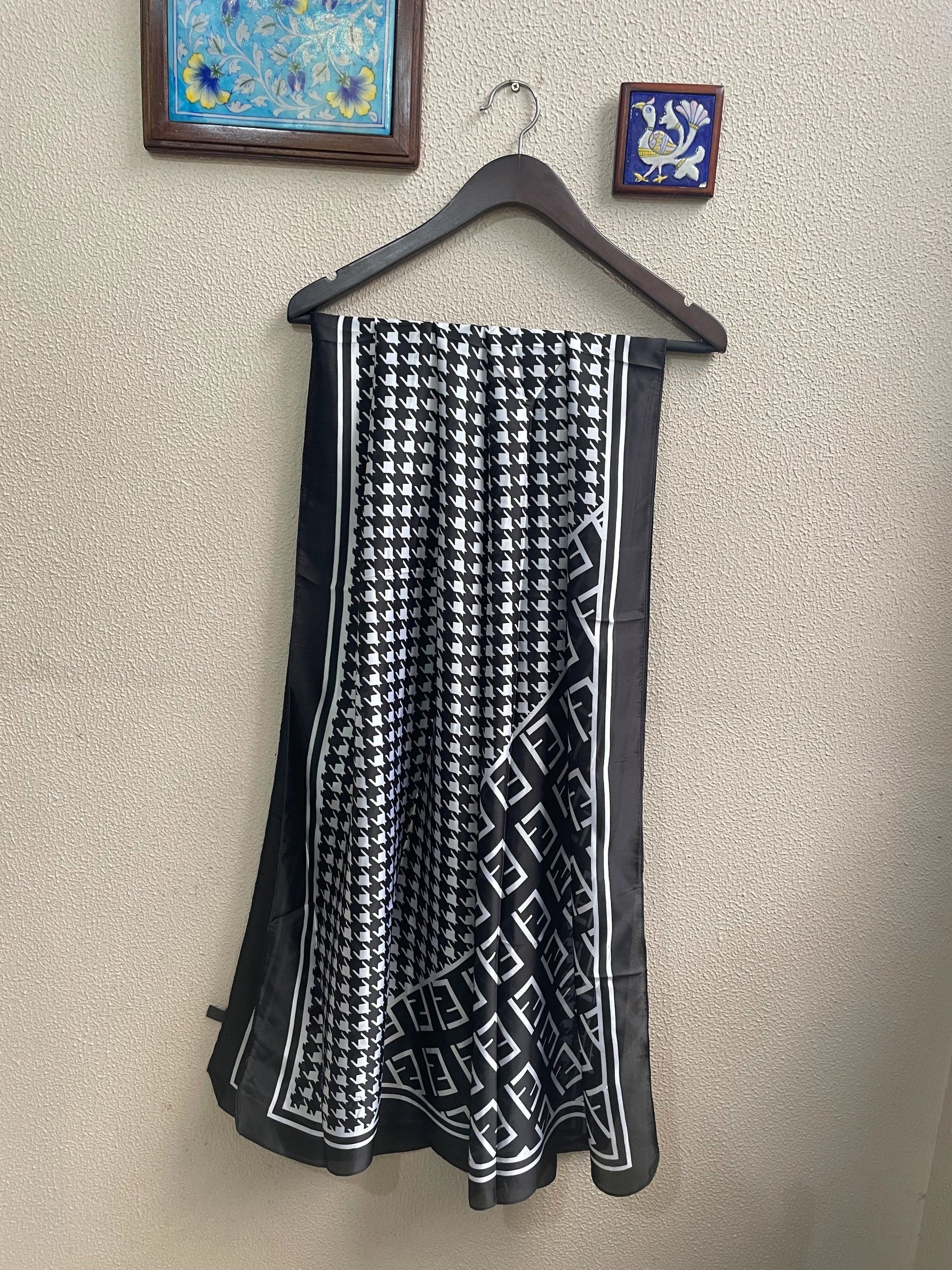 Elevate your wardrobe with this luxurious silk-feel satin scarf. Featuring a timeless black and white houndstooth pattern complemented by a modern monogram border, this 90 x 180 cm scarf is the definition of chic.