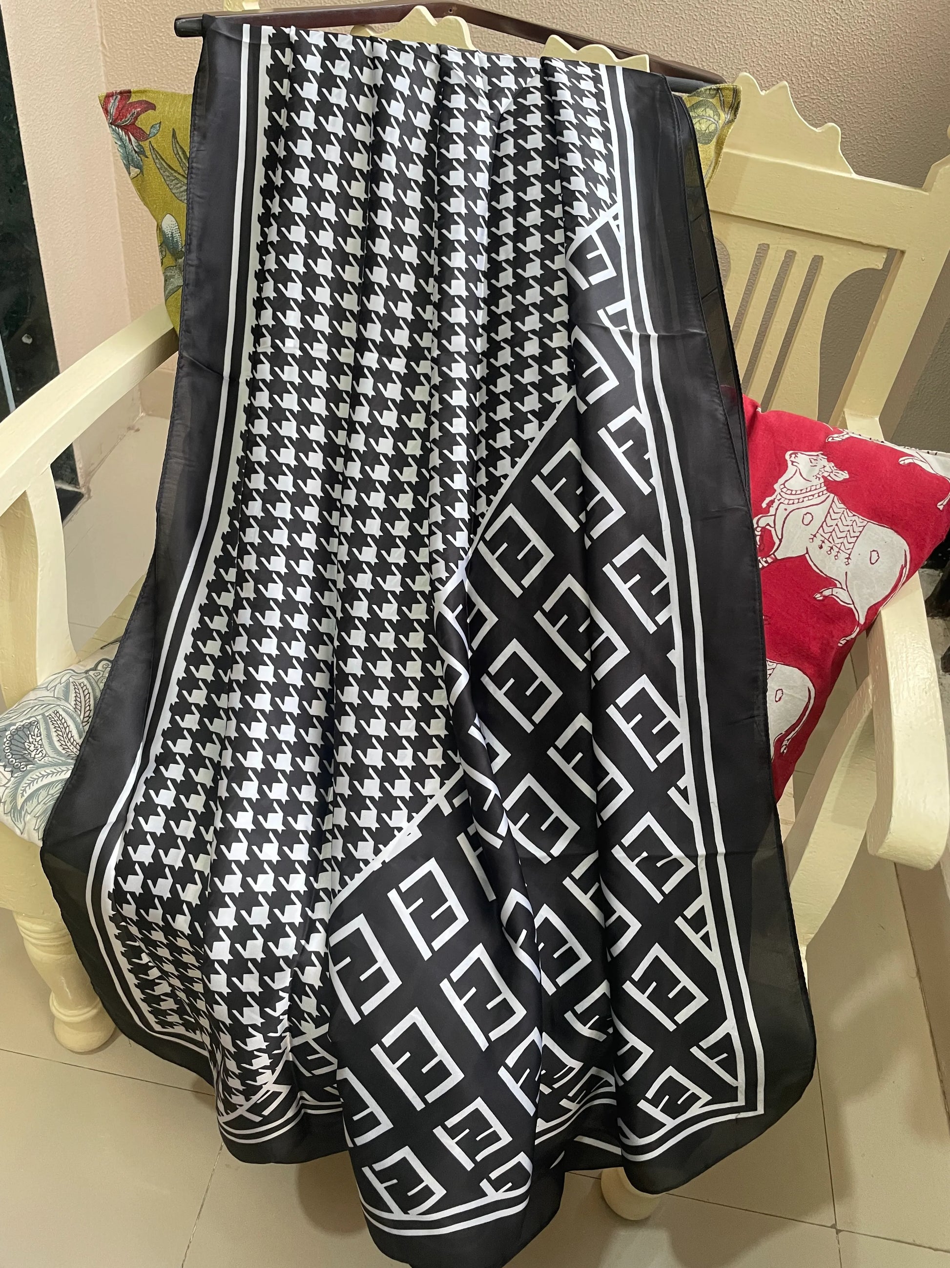 Elevate your wardrobe with this luxurious silk-feel satin scarf. Featuring a timeless black and white houndstooth pattern complemented by a modern monogram border, this 90 x 180 cm scarf is the definition of chic.
