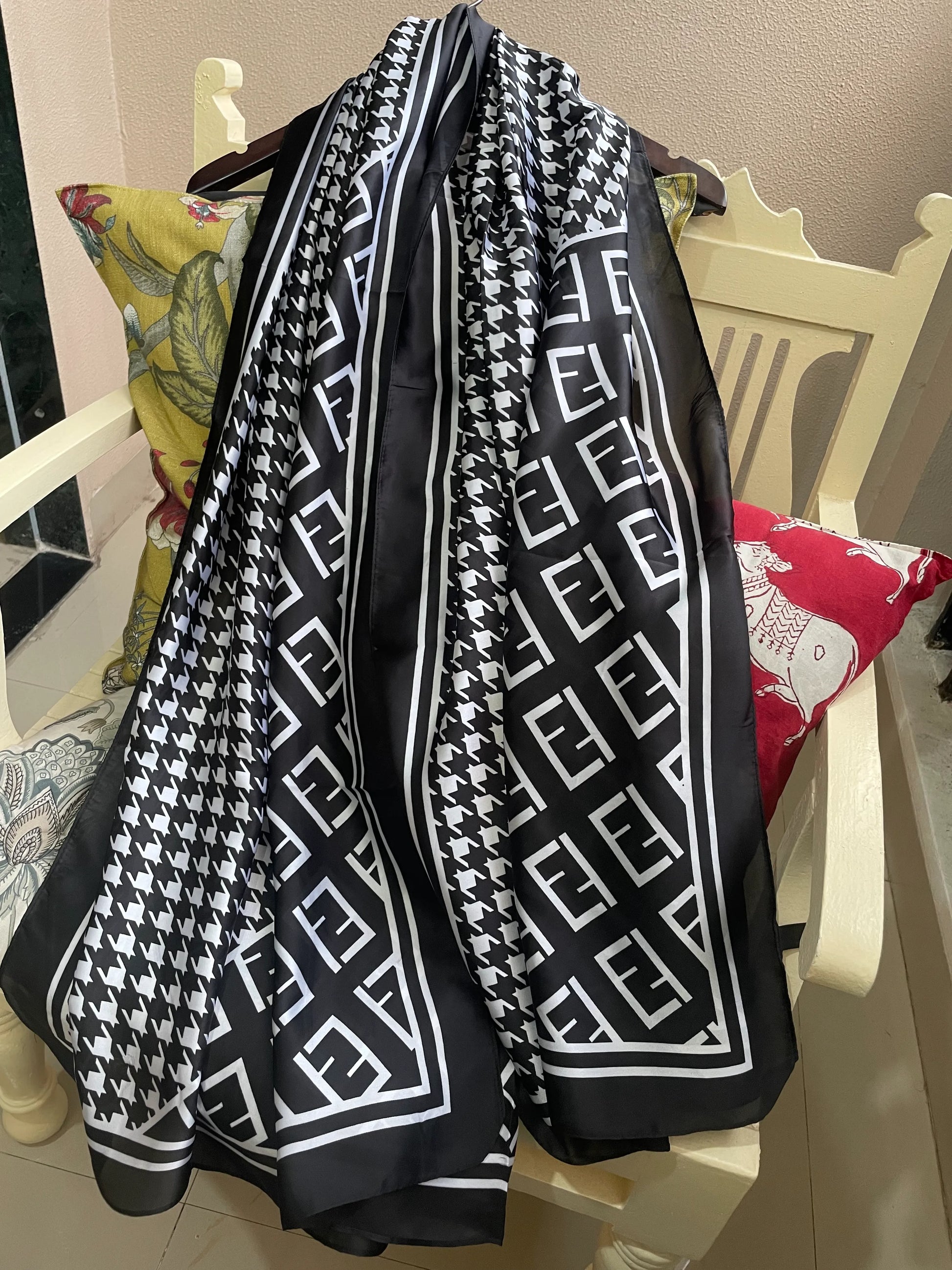 Elevate your wardrobe with this luxurious silk-feel satin scarf. Featuring a timeless black and white houndstooth pattern complemented by a modern monogram border, this 90 x 180 cm scarf is the definition of chic.