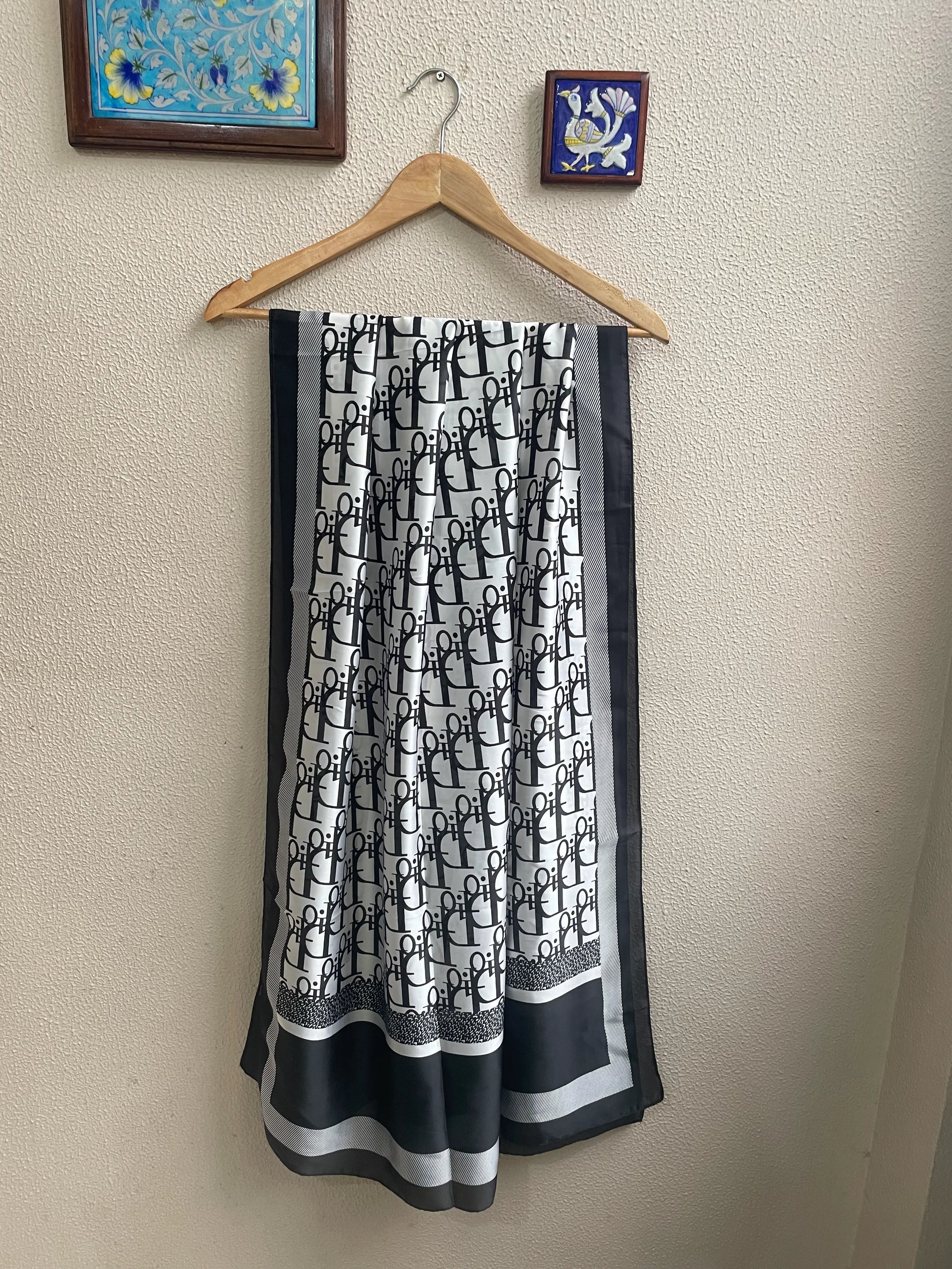 Elevate your style with this luxurious silk-feel satin scarf. Featuring a bold black and white monogram print with elegant contrasting borders, this 90 x 180 cm scarf is the epitome of chic sophistication.