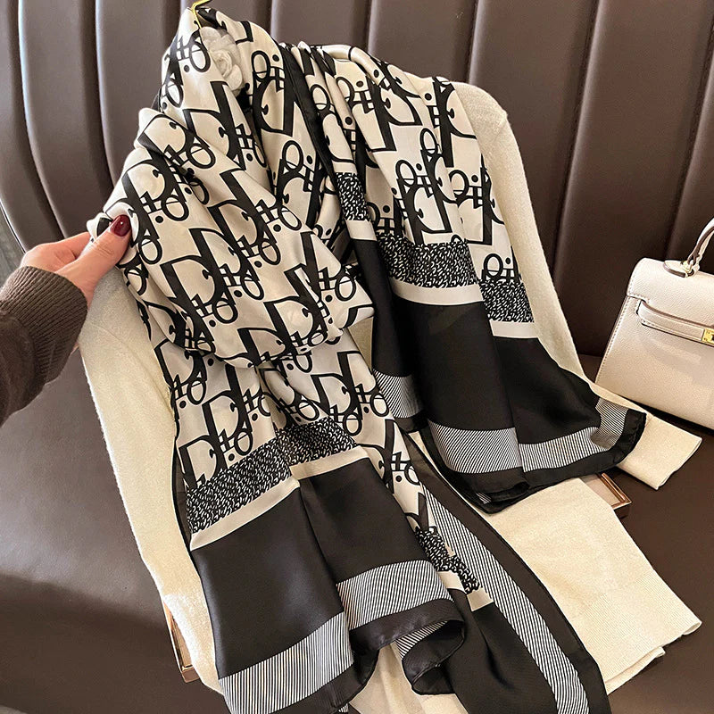 Elevate your style with this luxurious silk-feel satin scarf. Featuring a bold black and white monogram print with elegant contrasting borders, this 90 x 180 cm scarf is the epitome of chic sophistication.